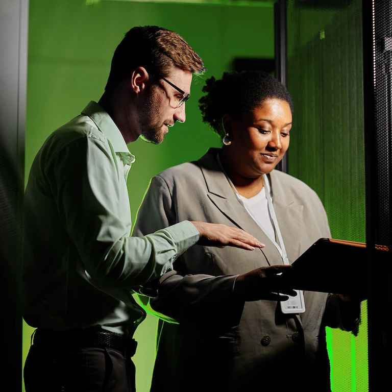 Two people looking at a laptop in a server room